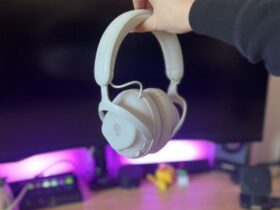 Alienware Pro Wireless headset being held my a reviewer against a PC setup