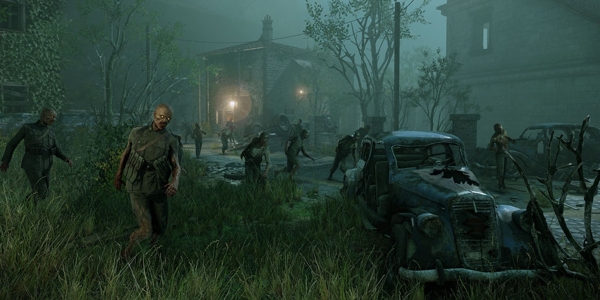 A village landscape at night, filled with dilapidated buildings, cars, and, of course, zombies.