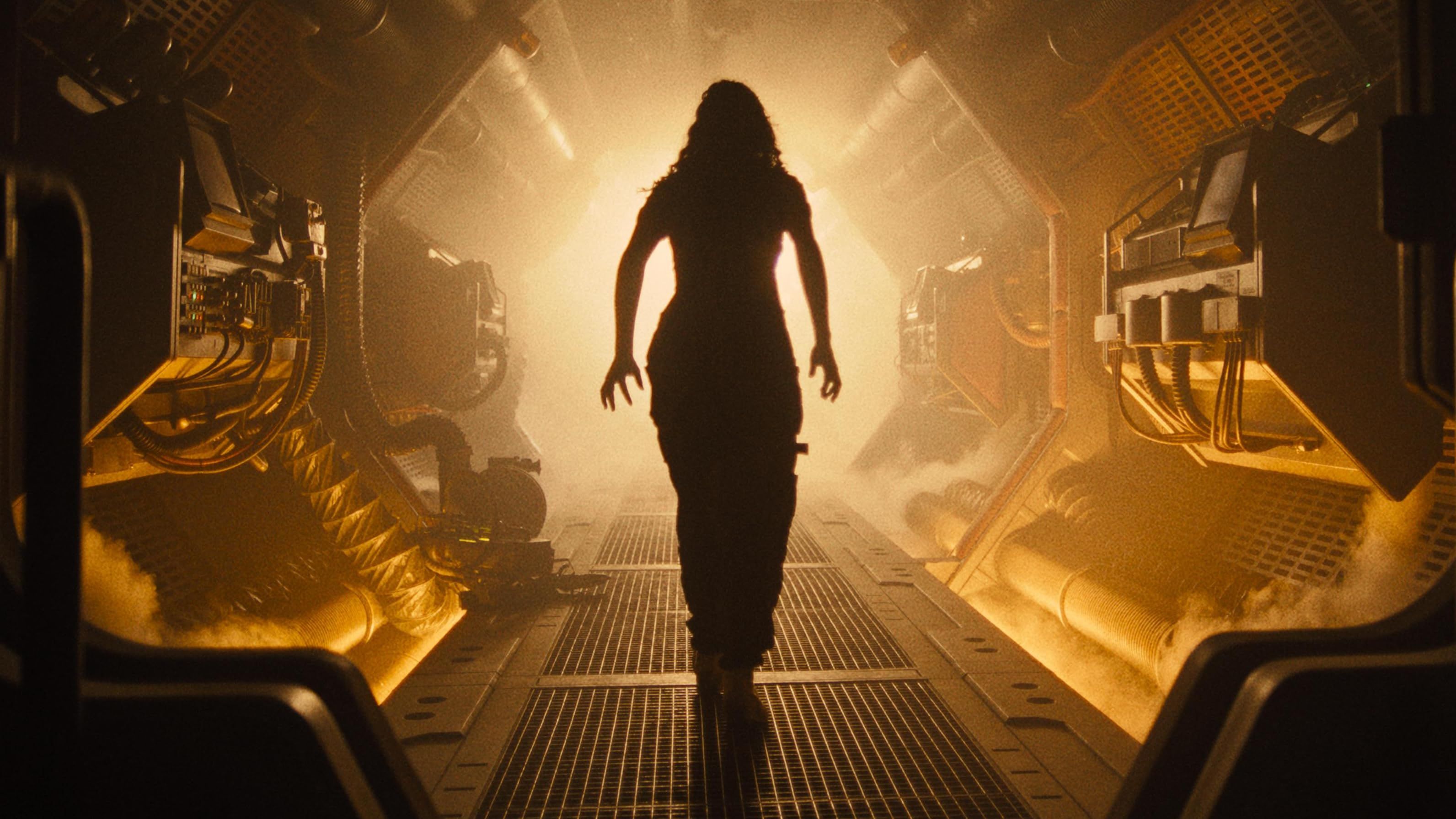 Alien Romulus woman walking down an orange-tinted corridor in a spaceship