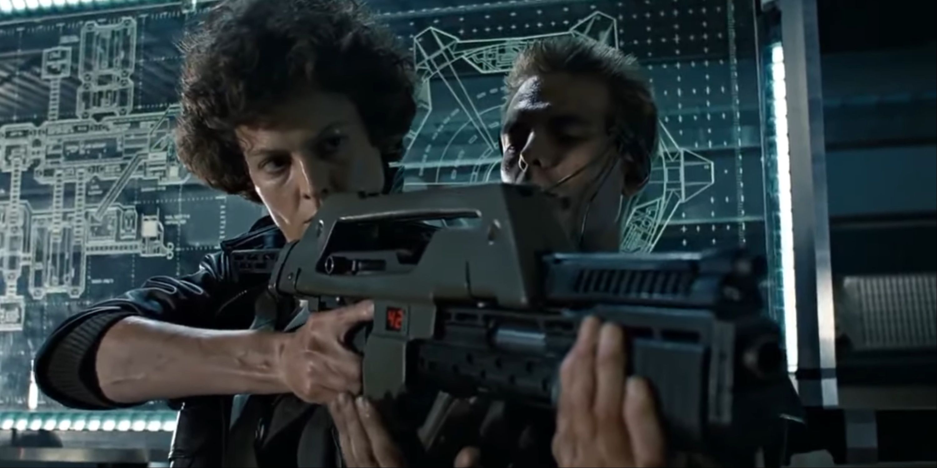 Sigourney Weaver's Ellen Ripley holding and aiming a pulse rifle as Hicks guides her on how to fire it.