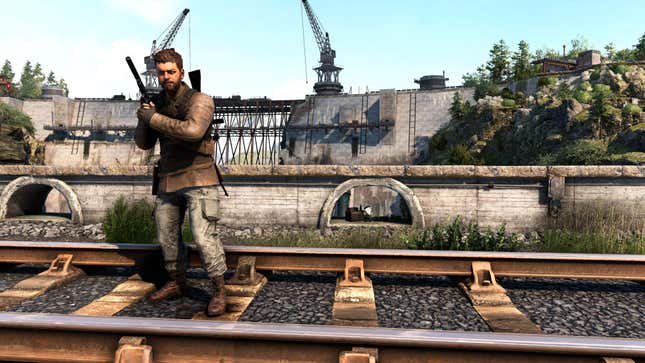 The protagonist of Sniper Elite: Resistance stands on train tracks while the French Resistance Gnome stands in the background.