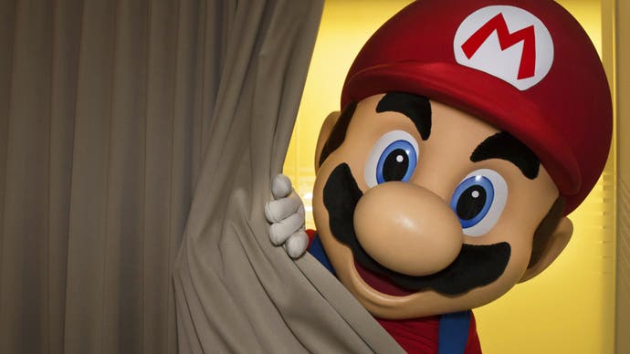 Someone in a Mario costume peeks out from behind a curtain.