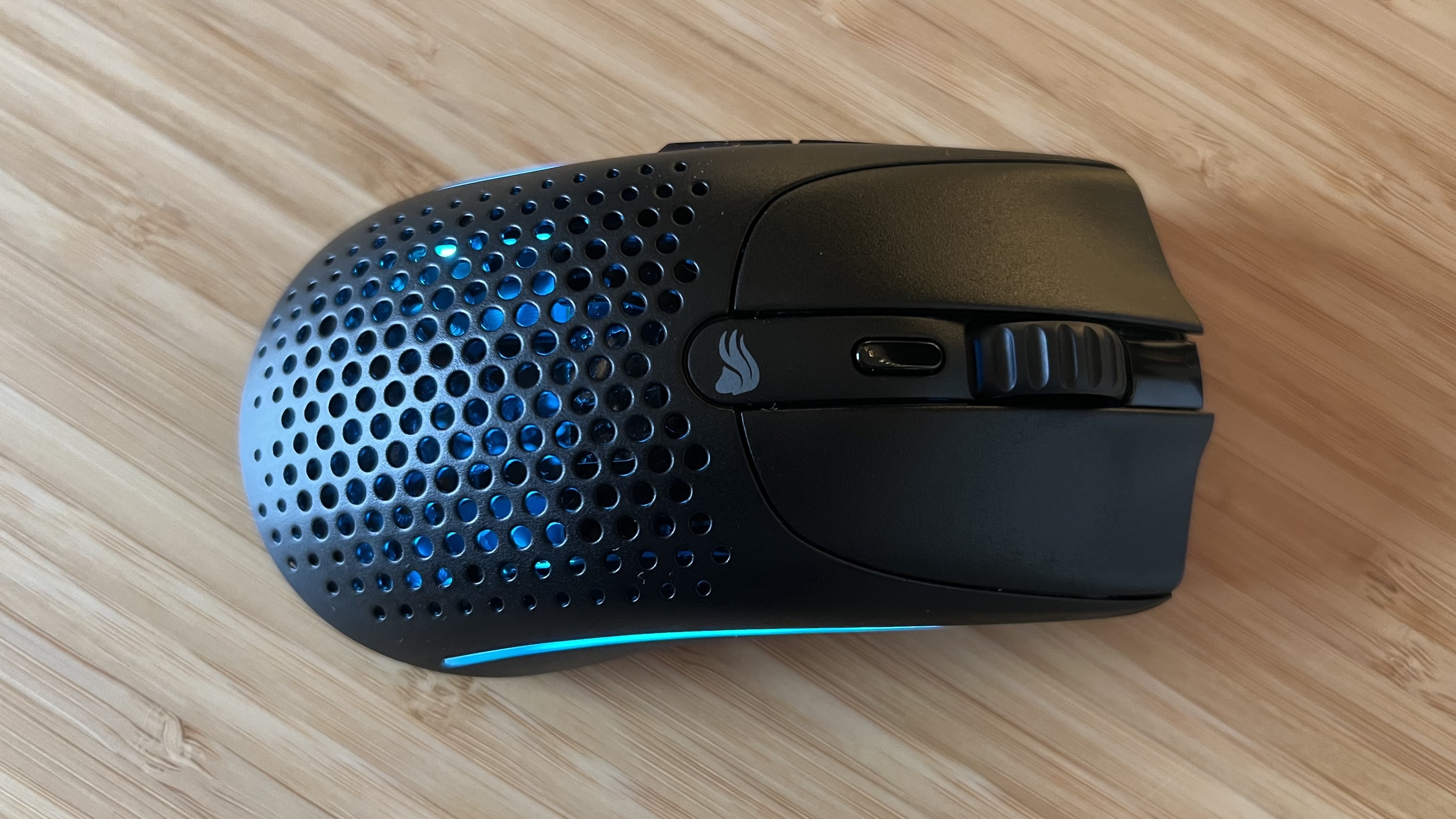 Glorious Model O 2 Mini Wireless gaming mouse with blue RGB lighting on a wooden desk