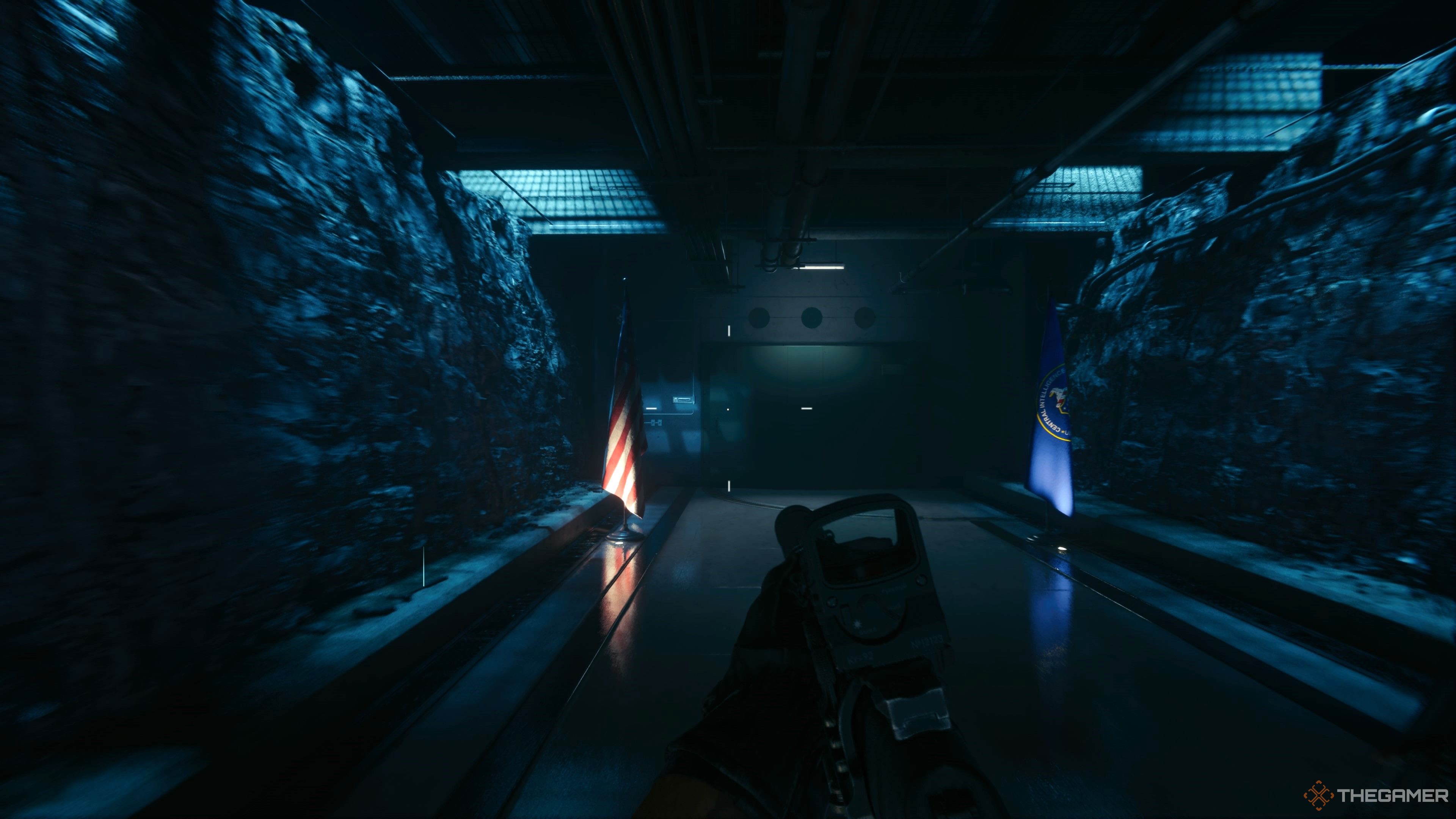 An image with the player in one of the main story missions. The player is making their way through a tunnel leading to the entrance of the CIA Blacksite. Crosshairs are visible on screen with the weapon pointed forwards. Rock walls and flags adorn the tunnel.