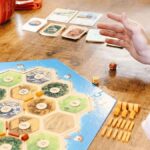 Someone rolls dice at the table while playing Catan