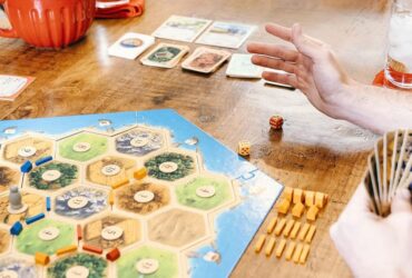 Someone rolls dice at the table while playing Catan