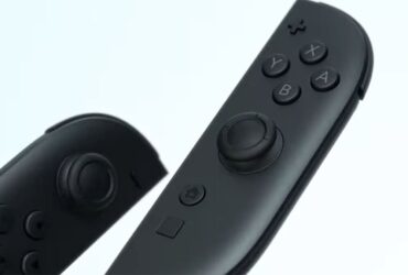 The new Nintendo Switch 2 Joy-Cons on a white background. They're black with some pops of colour around the sticks, and there's a new button under the home button