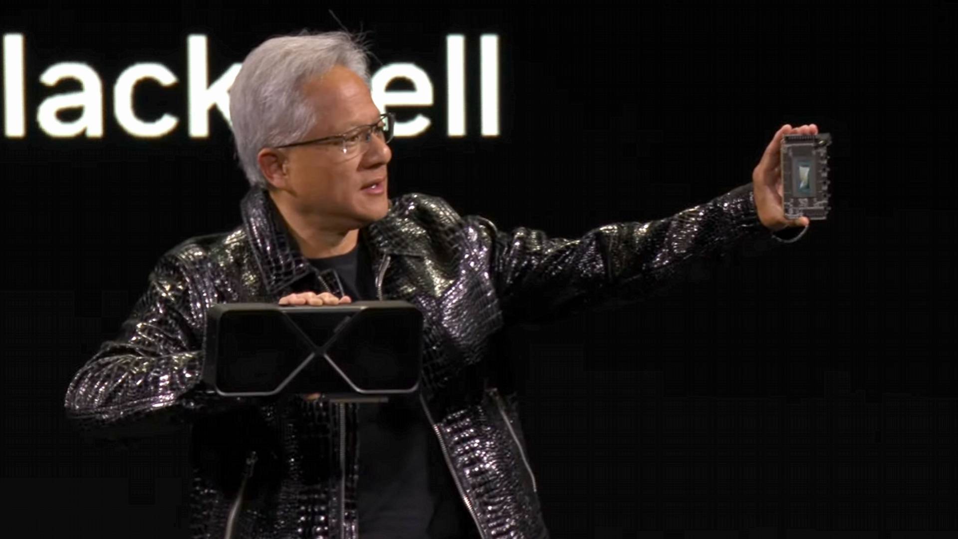 Nvidia CEO Jensen Huang holding RTX 5090 graphics card and GPU on stage