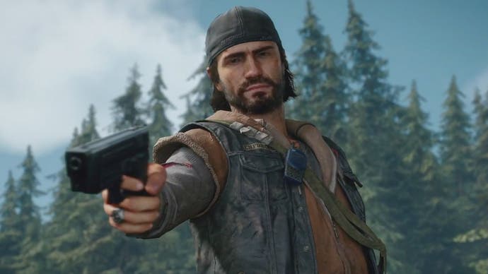 A screenshot of Days Gone protagonist Deacon St. John pointing a gun at something offscreen as a forest of pines looms behind him.