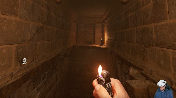 A small lighter flame illuminates a dark, trap-filled tomb.