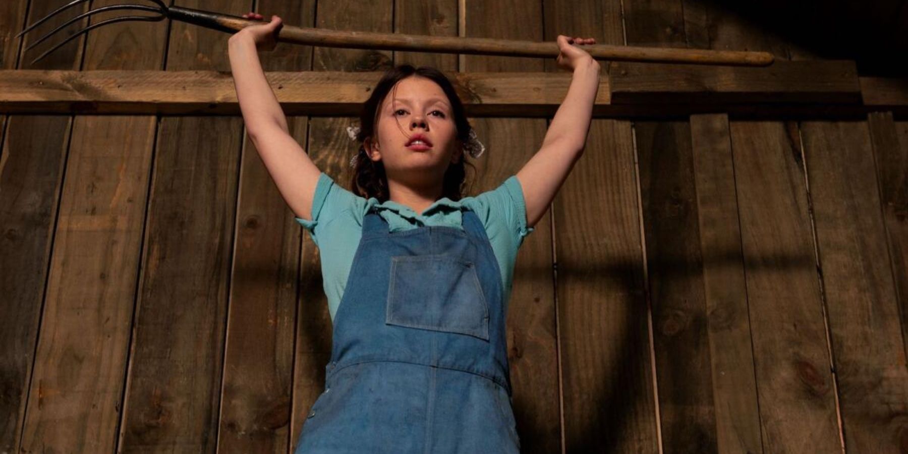 Mia Goth holding an axe in a barn in Pearl