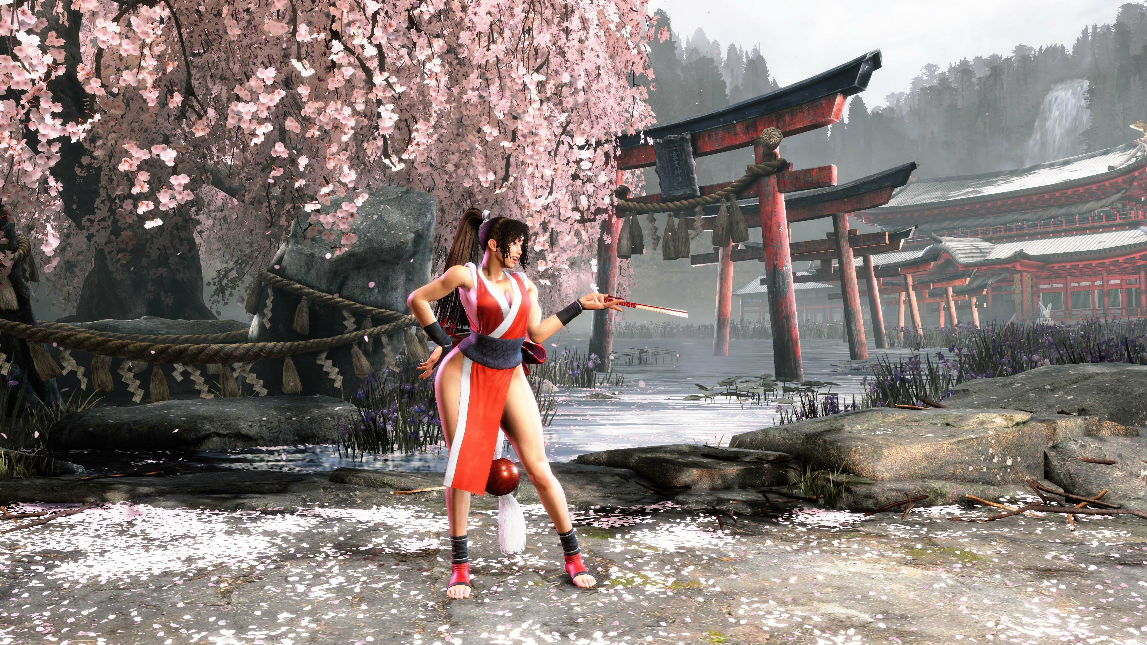 Mai Shiranui standing in front of the Genbu Temple with her right hand on her hip and the other extended forward with her signature tessen wielded in Street Fighter 6.