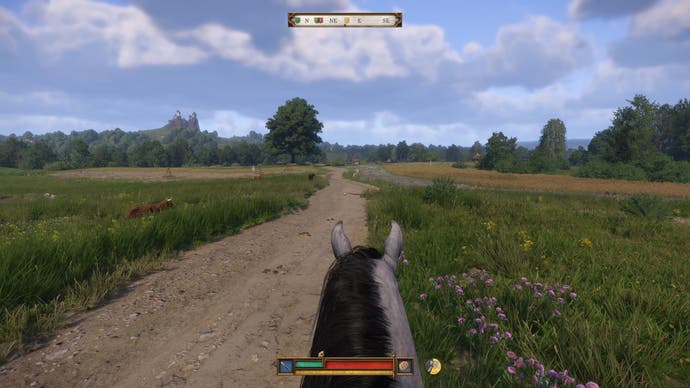 The player rides their horse down a muddy track surrounded by fields in Kingdom Come Deliverance 2