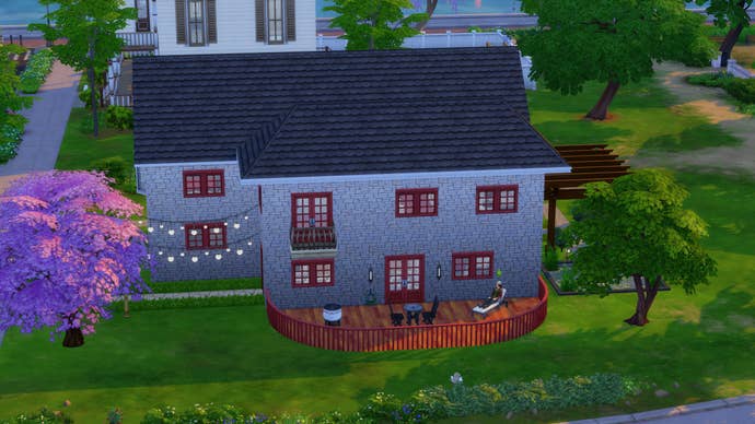 A custom house in The Sims 4 with a sim sitting outside it.