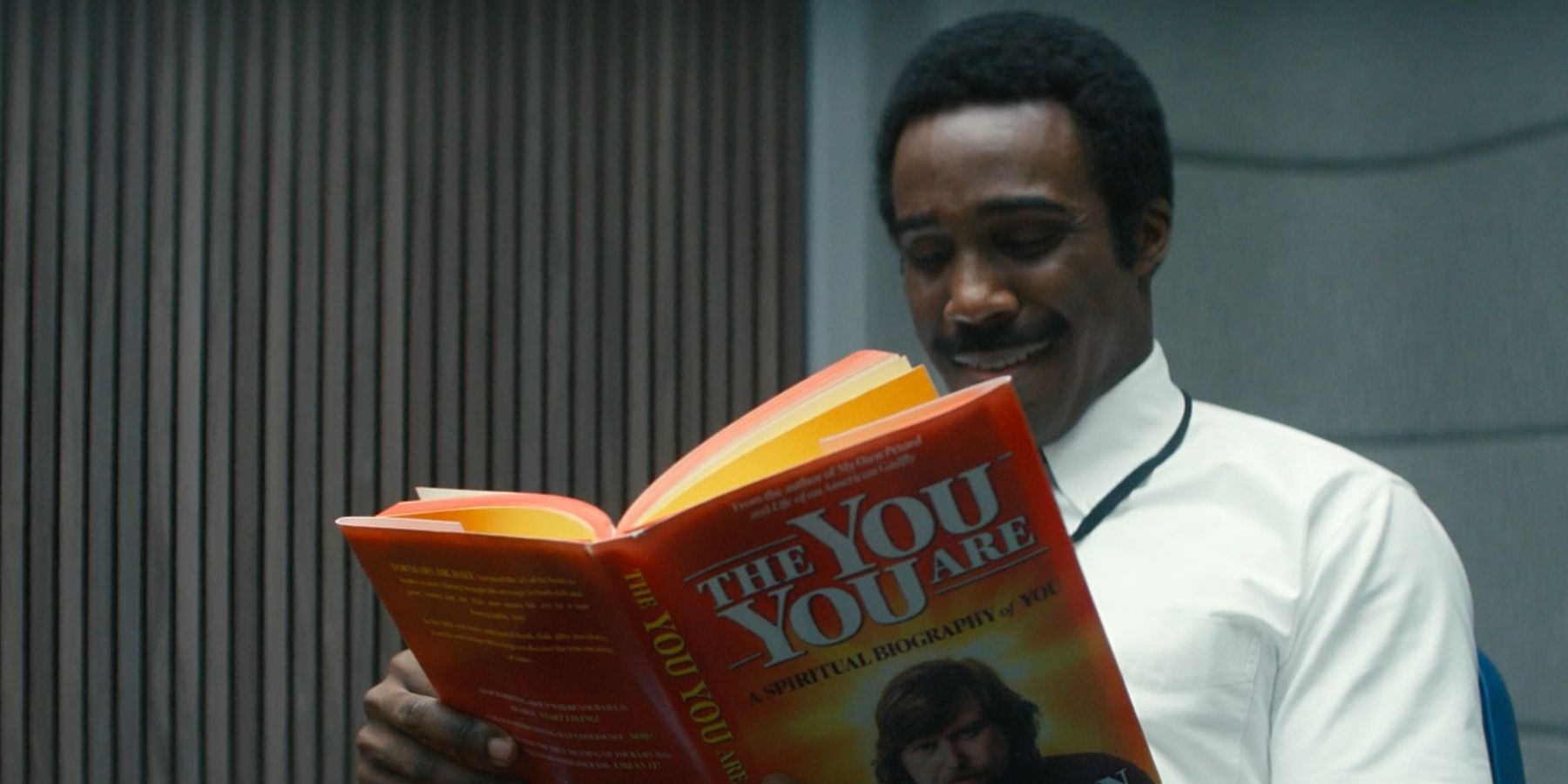 Mr. Milchick (Tramell Tillman) reads Ricken's self help book in Severance