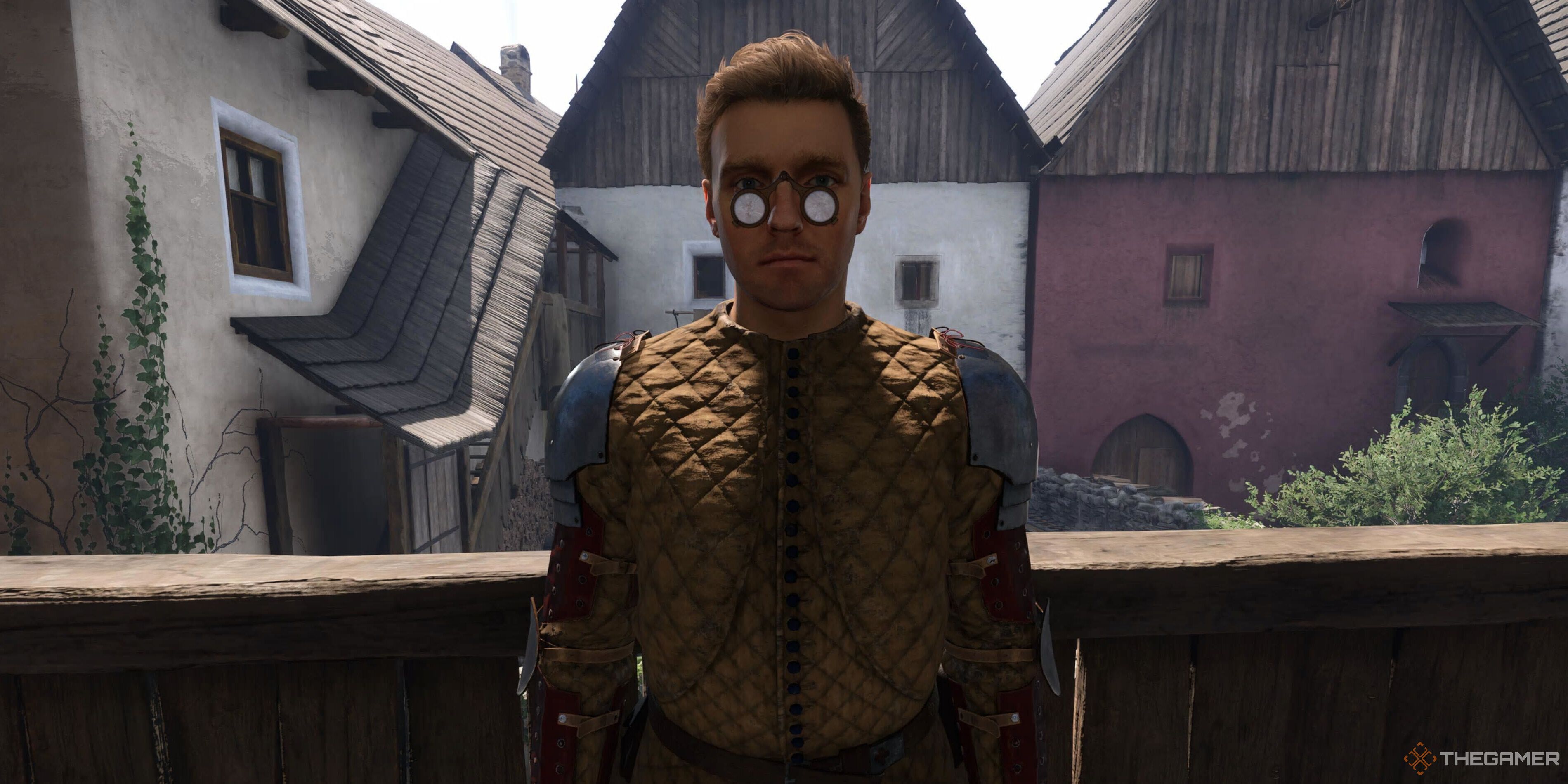 Henry standing in front of buildings in Kingdom Come: Deliverance 2.