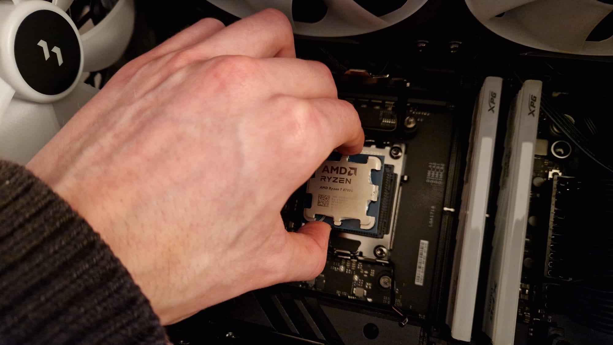 A AMD Ryzen 7 8700G being put into it's socket by a reviewer