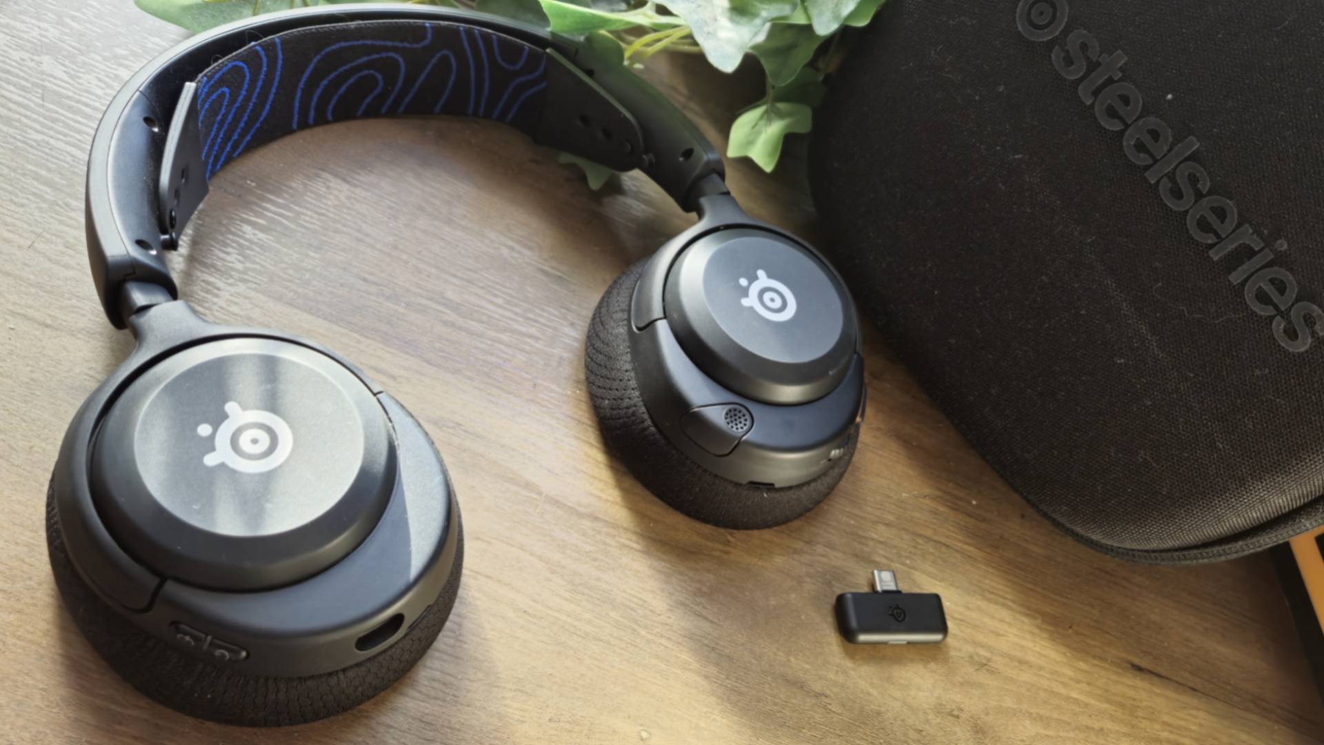 The SteelSeries Arctis Nova 5P wireless gaming headset on a wooden desk.