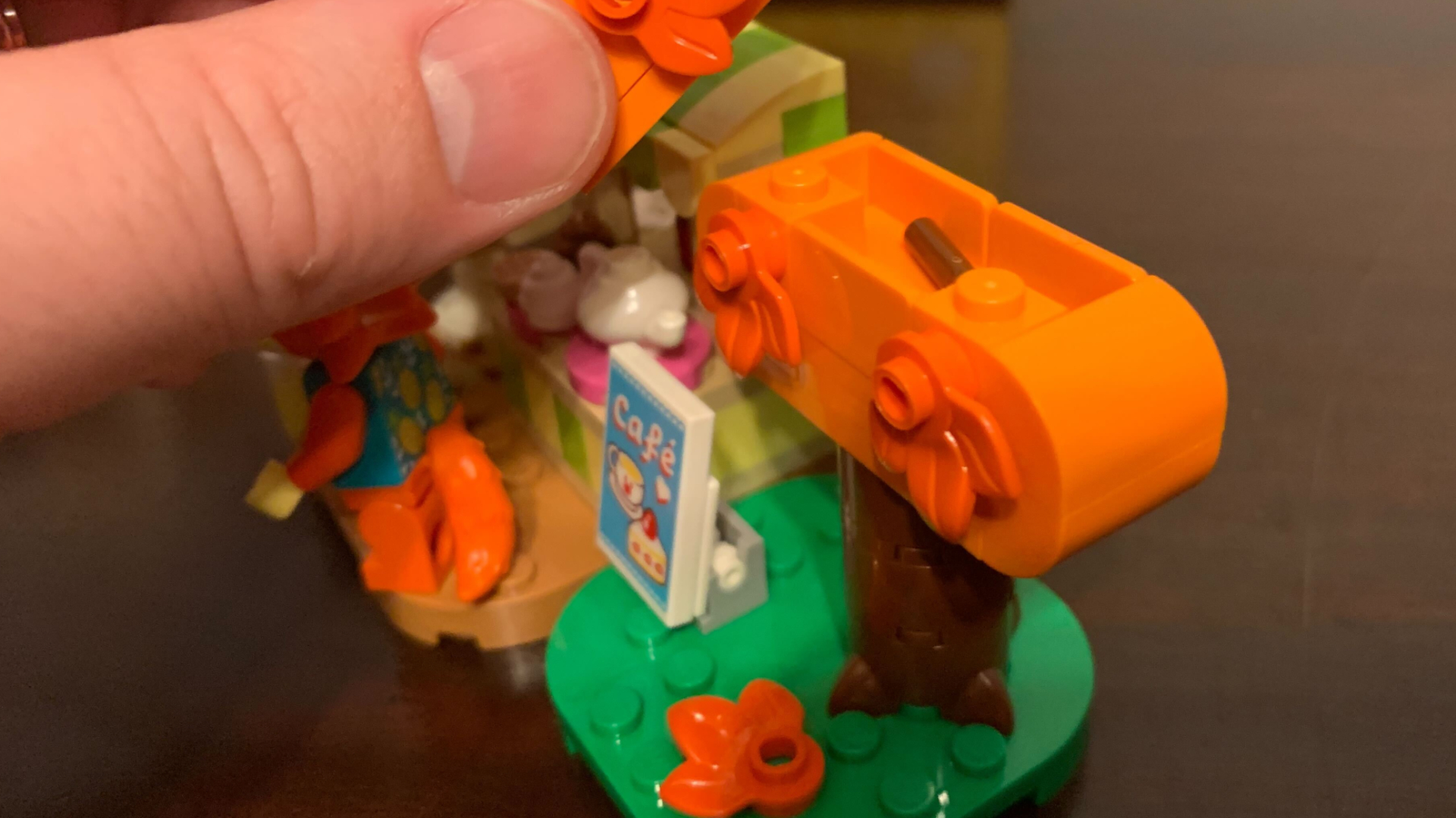 A hand removes the top of a Lego Animal Crossing tree