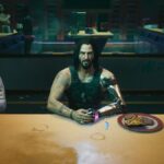 Cyberpunk 2077: Johnny Silverhand sits at a restaurant table with his hands together next to a plate of food