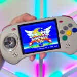 Hand holding Anbernic RG ARC-D handheld with Sonic the Hedgehog 2 gameplay on screen