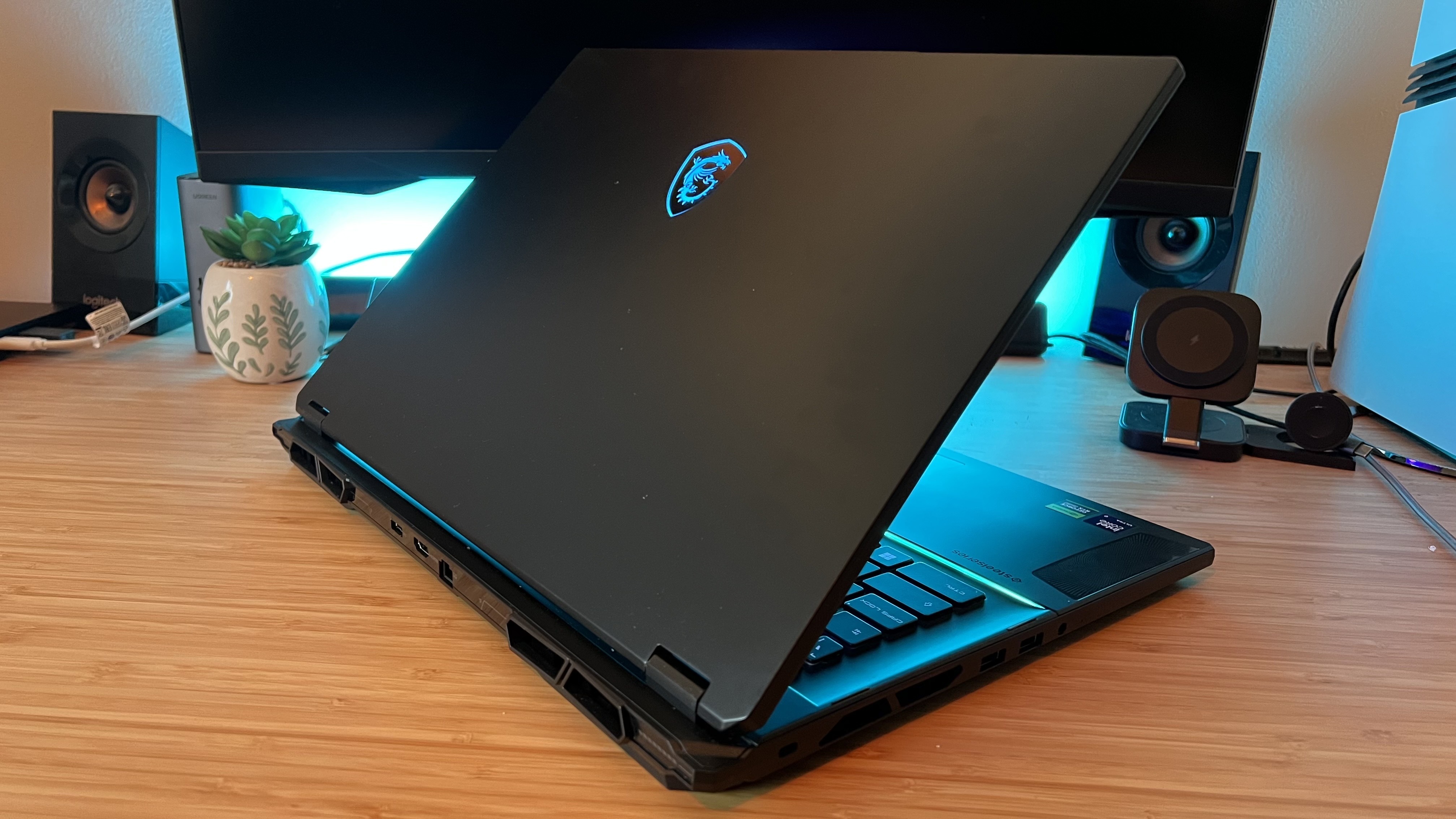 Back panel of MSI Stealth 18 AI Studio gaming laptop with logo in blue RGB on a wooden desk