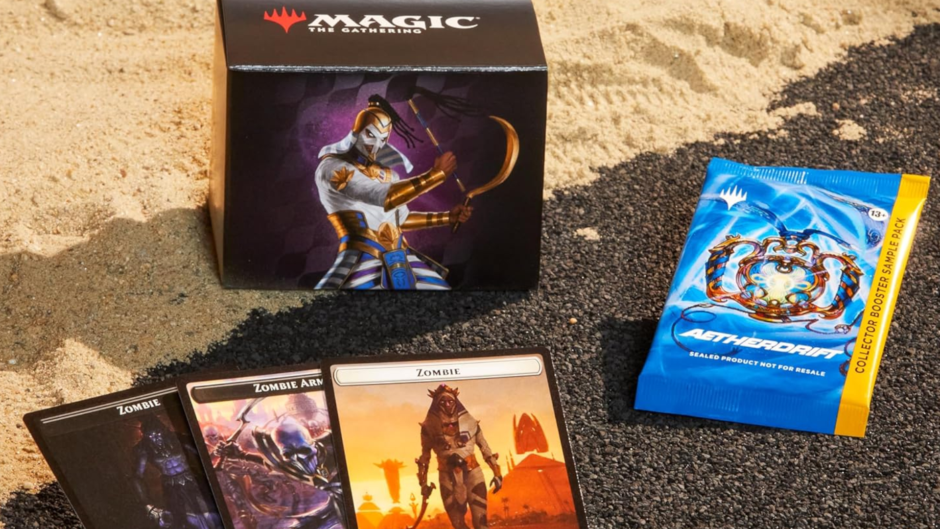 Eternal Might Commander box on sand, behind three token cards and a Collector Booster pack on asphalt