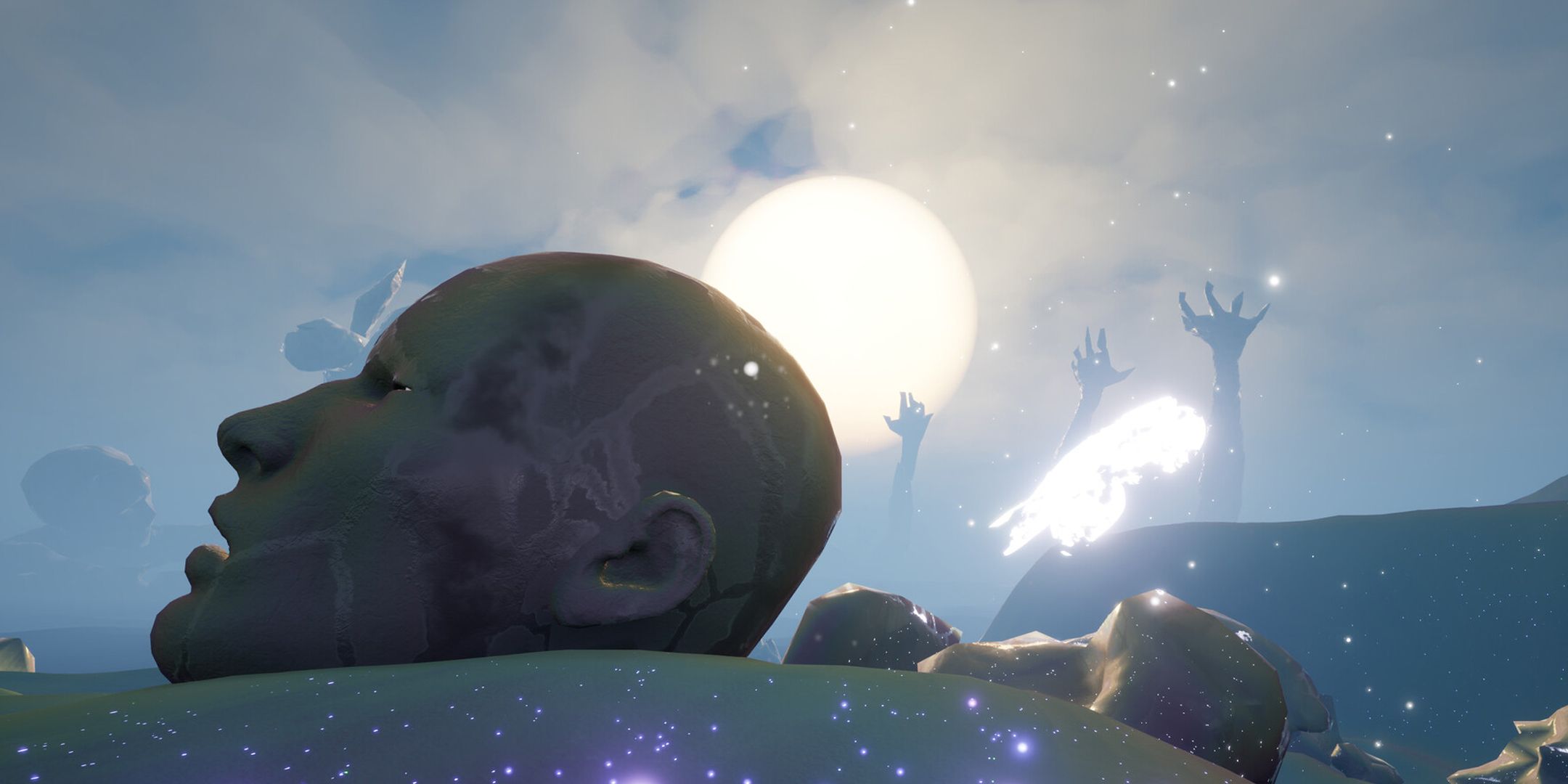 Giant disembodied stone head lying on sand with huge hands reaching out into the sky in the background.