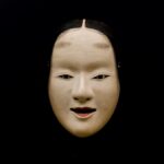 A noh mask on a black background