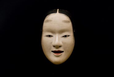 A noh mask on a black background