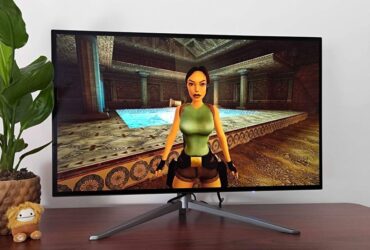 27-inch KTC G27P6 OLED monitor on desk next to plant with Tomb Raider Trilogy gameplay on screen