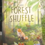 Forest Shuffle card game held up beside a plant