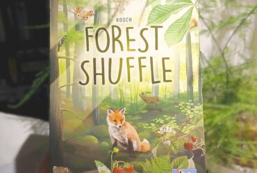 Forest Shuffle card game held up beside a plant