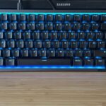 NZXT Function Elite Mini TKL gaming keyboard with blue RGB lighting set against a blue gaming setup