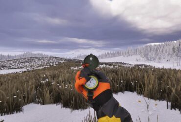 A gloved hand holding a compass in a snowy field