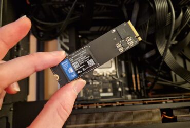 The WD Blue SN5000 4TB SSD being held above a gaming PC by a reviewer