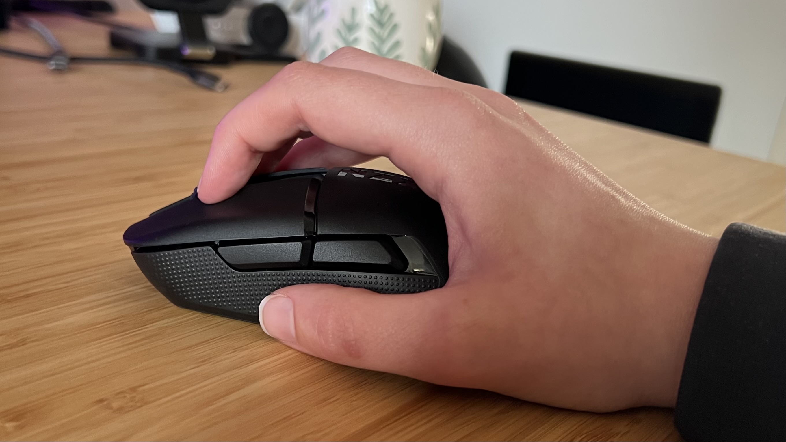 Hand using the NZXT Lift Elite Wireless gaming mouse in a claw grip on a desk