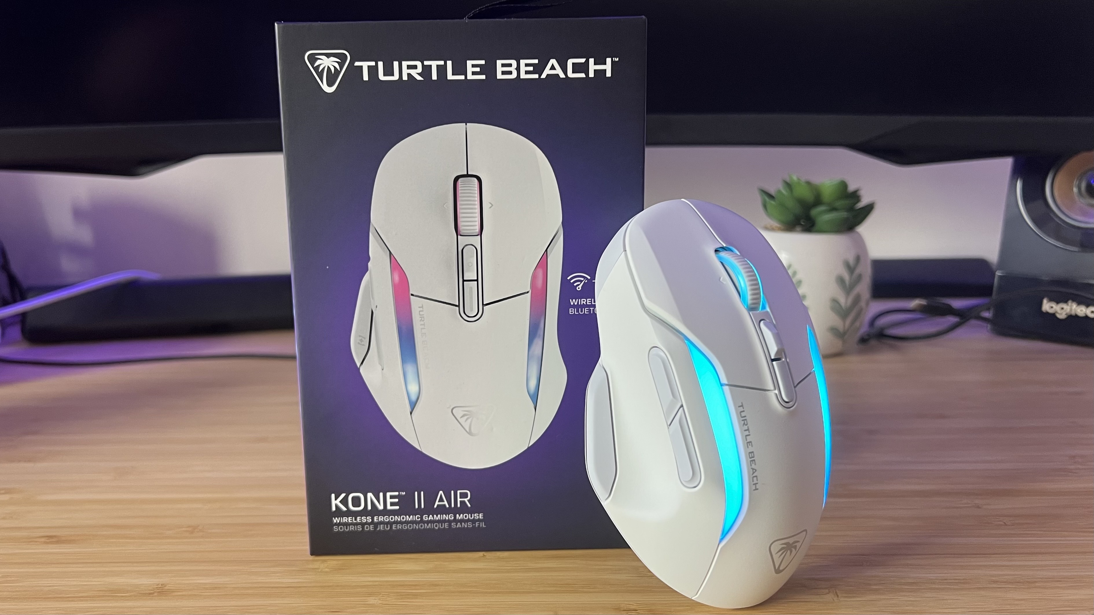 Turtle Beach Kone II Air gaming mouse standing against product packaging on a wood gaming desk