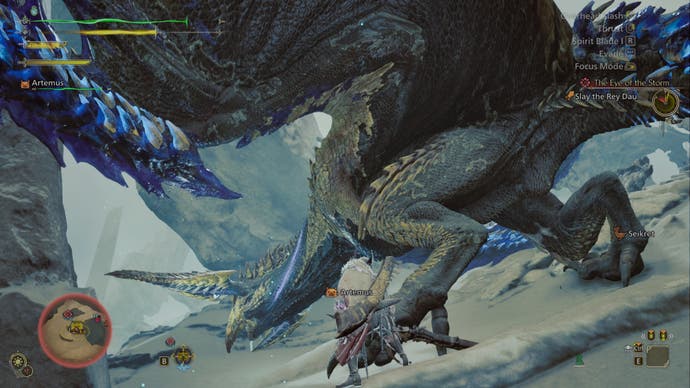 A hunter attacks the foot of the Rey Dau monster on a sand dune in Monster Hunter Wilds.