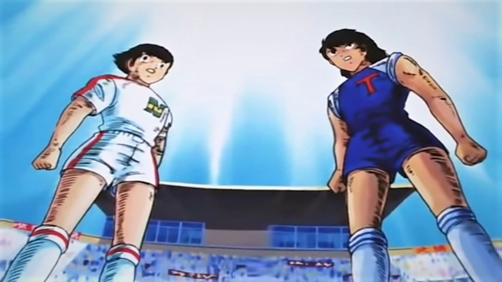 A screenshot of Tsubasa, shocked, standing next to his rival with the crowd and the sky as the background.