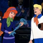 Velma, Daphne, Fred, Shaggy, and Scooby-Doo looking at a giant key which is also a clue