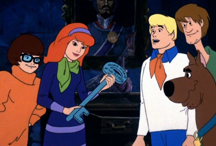 Velma, Daphne, Fred, Shaggy, and Scooby-Doo looking at a giant key which is also a clue