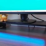 Razer Monitor Stand Chroma on desk with blue lighting reflecting off surface and Alienware gaming monitor on top.