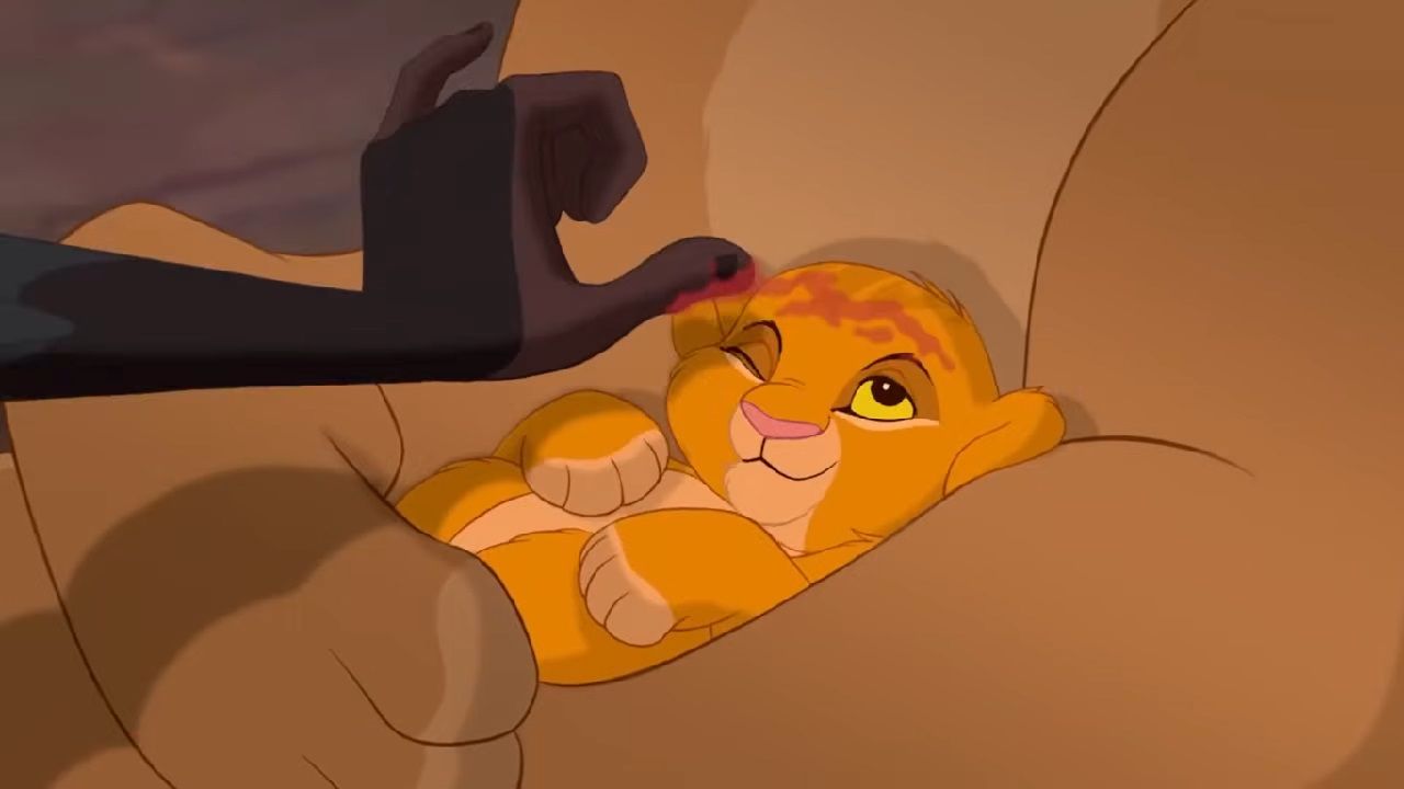 A still frame from Disney's The Lion King, showing a young Simba having the juice of the jujube fruit smeared across his forehead by Rafiki.