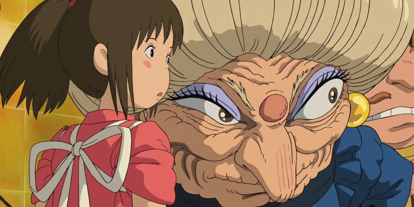 Chihiro, a young girl in a pink outfit, and Yubaba, a short, older woman, stare at something in the bathhouse in Spirited Away.
