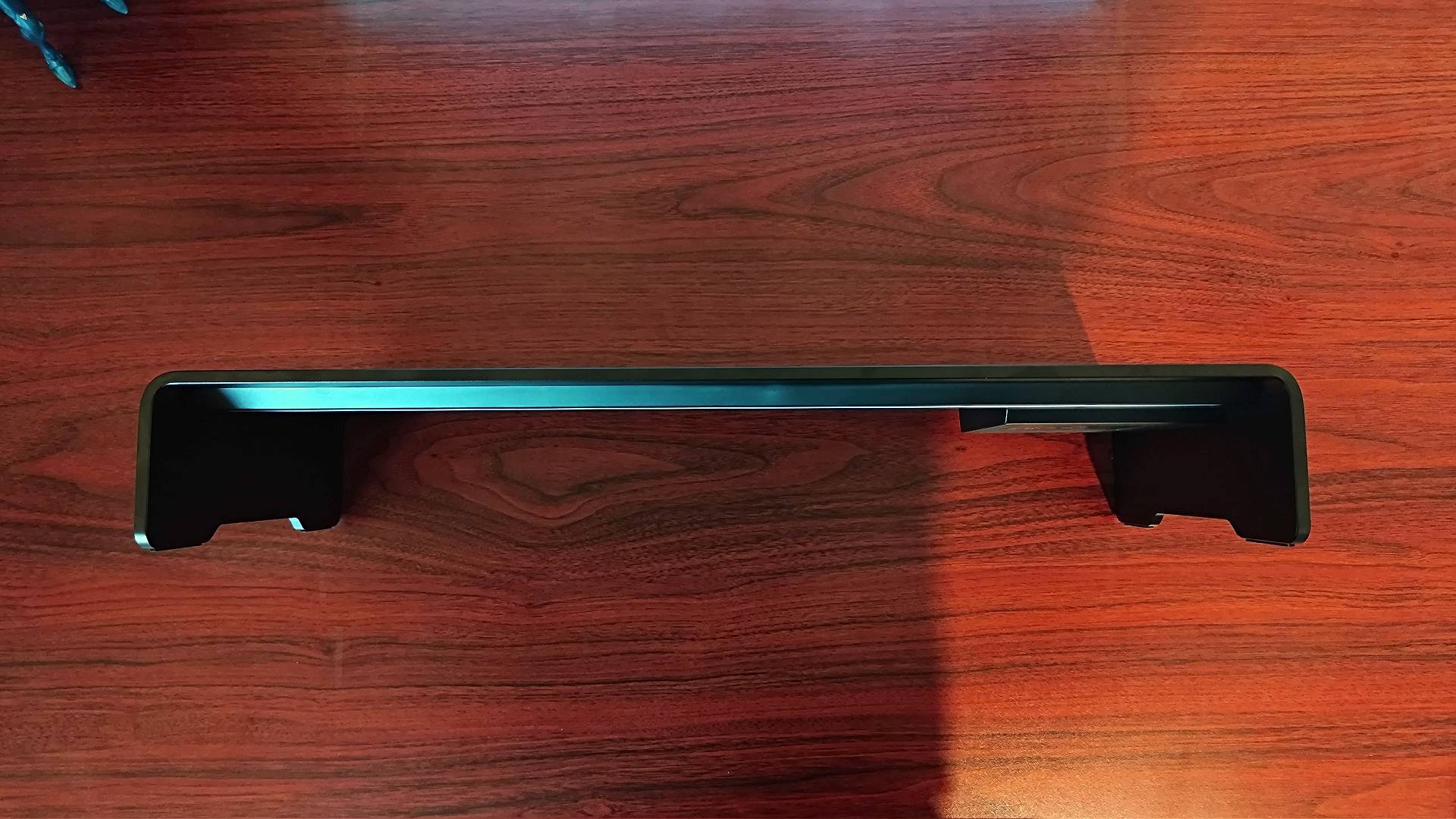 Razer Monitor Stand Chroma lying on woodgrain desk with front facing upwards.
