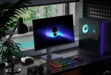 Alienware AW2725DM monitor sitting on desk next to Aurora R16, RGB keyboard, headset, and plants