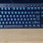 Logitech G Pro X TKL Rapid gaming keyboard on a wooden desk with blue lighting