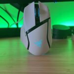 White Razer Basilisk V3 Pro 35K gaming mouse standing up against a green-lit setup