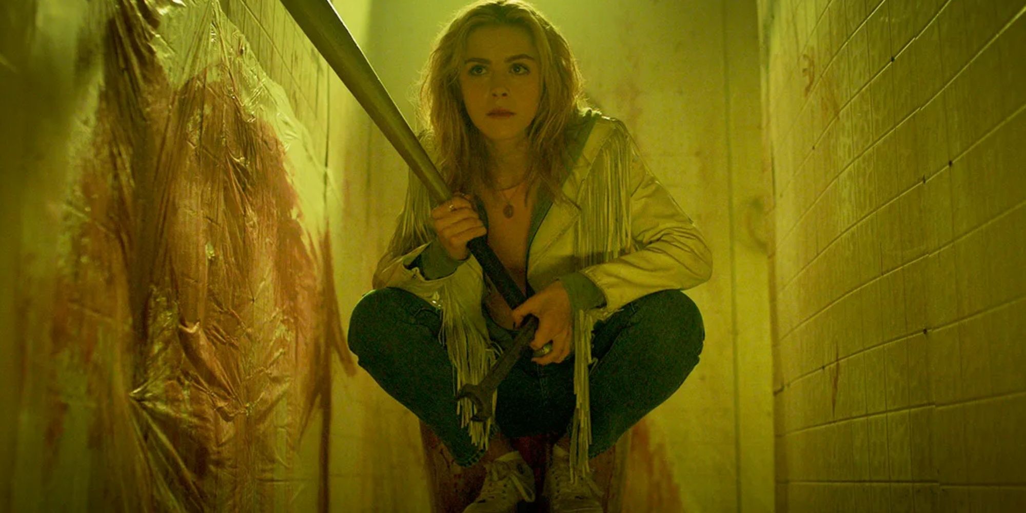 Kiernan Shipka in Totally Killer, crouching in wait for the serial killer. She is armed with a wrench and a baseball bat.